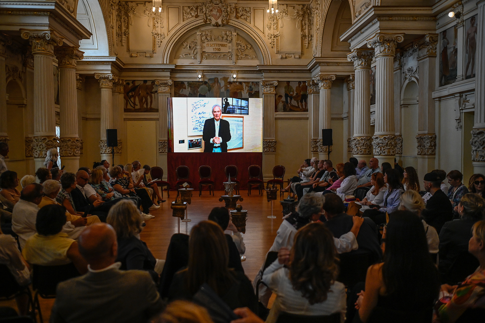 Festival di Spoleto event with speaker on screen in ornate historic hall