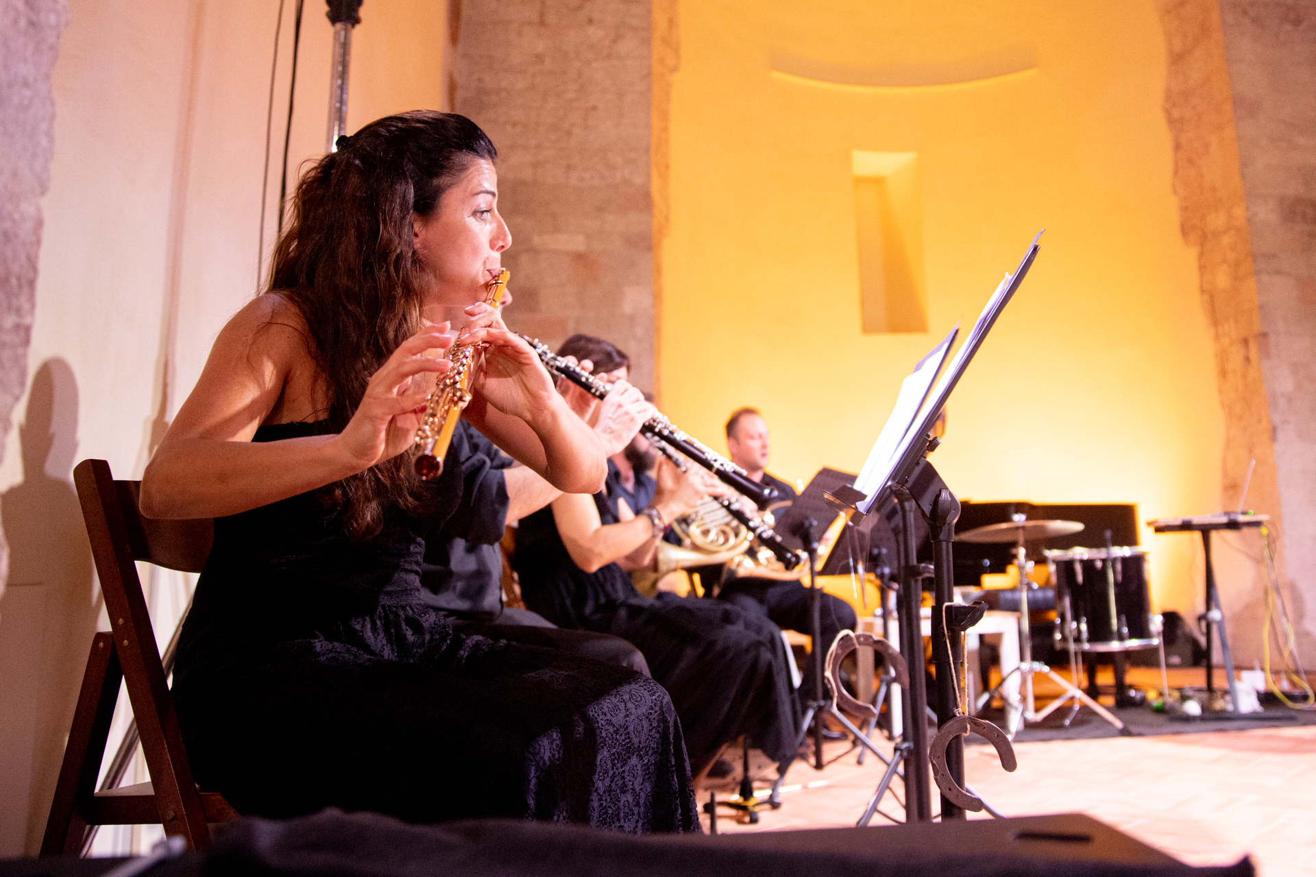 Flutist performing at Festival di Spoleto, seated with orchestra in background