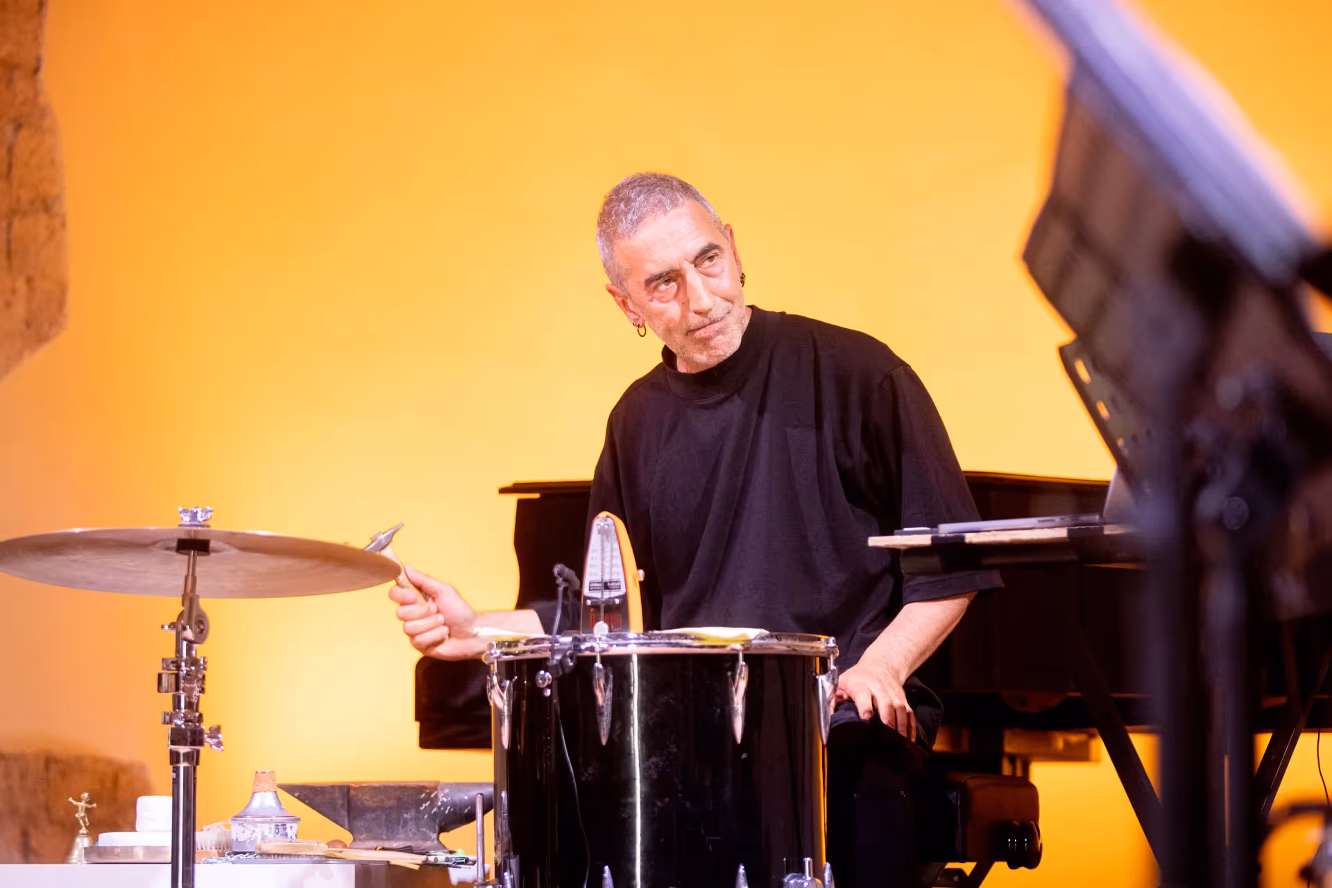 Musicista al Festival di Spoleto suona batteria con sfondo giallo intenso