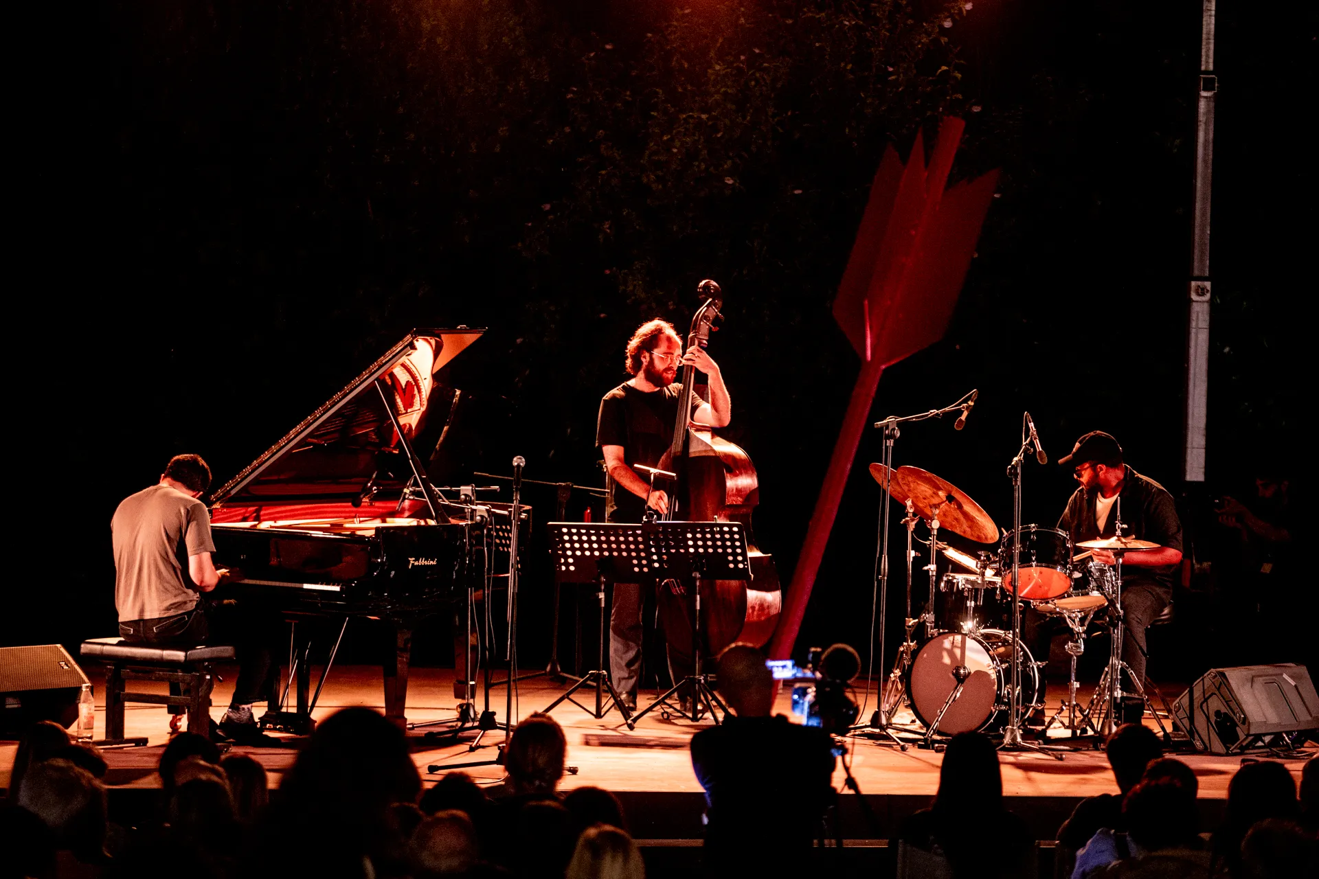 Jazz trio performing at Festival di Spoleto, dramatic stage lighting illuminates musicians