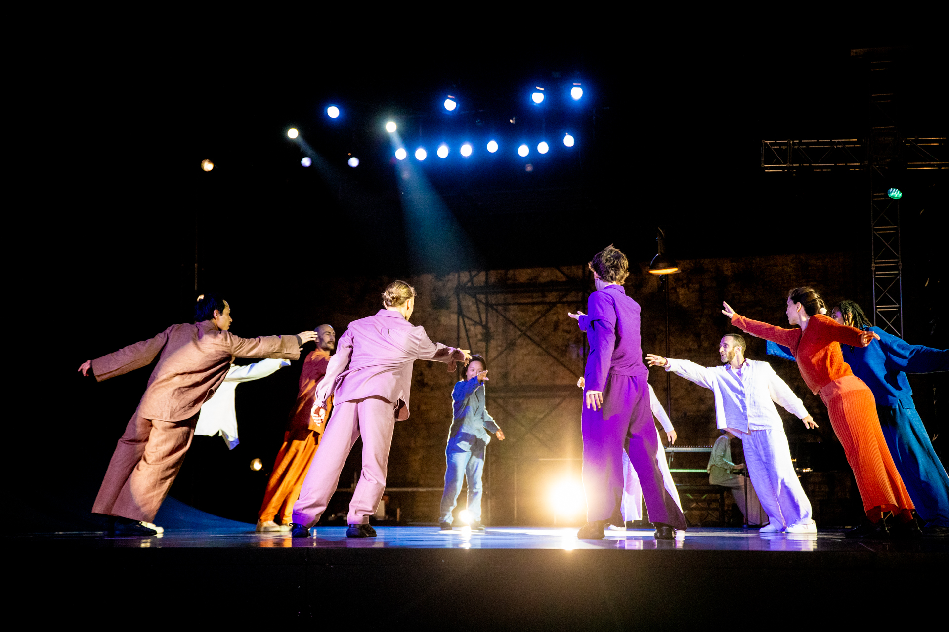 Performance colorata al Festival di Spoleto con ballerini in palcoscenico illuminato