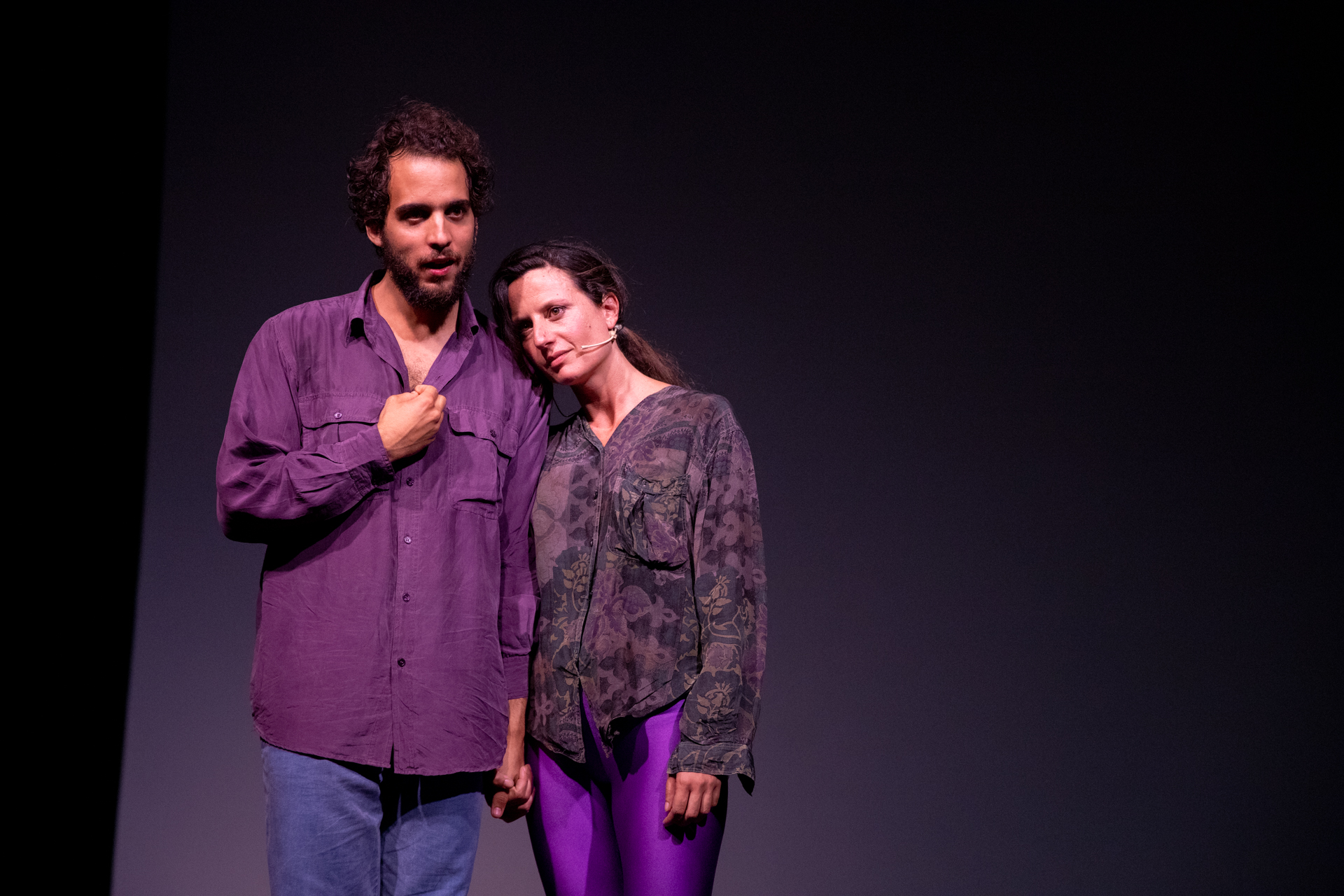 Attori sul palco durante il Festival di Spoleto, illuminati da luce viola