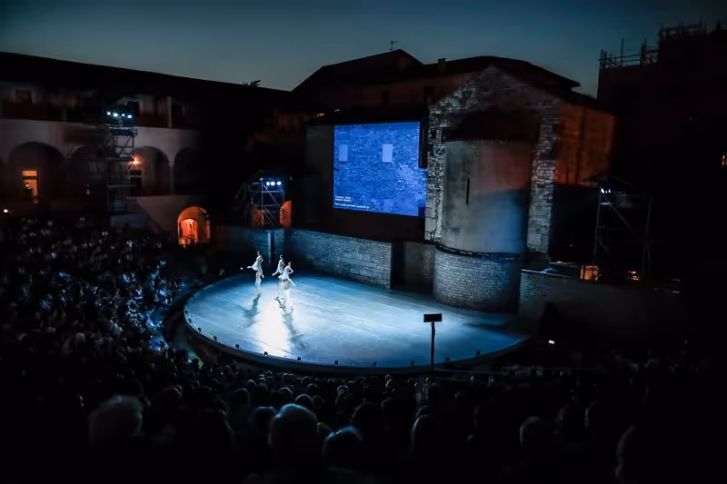 Performance serale al Festival di Spoleto, palcoscenico illuminato con danzatori