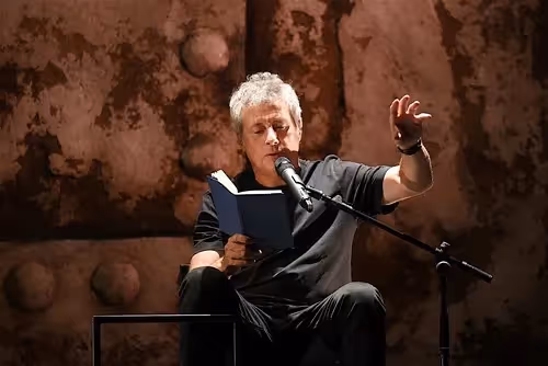 Performer reading at Festival di Spoleto, gesturing passionately on stage