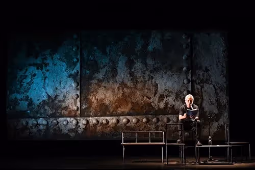 Solitary performer on stage at Festival di Spoleto with textured backdrop