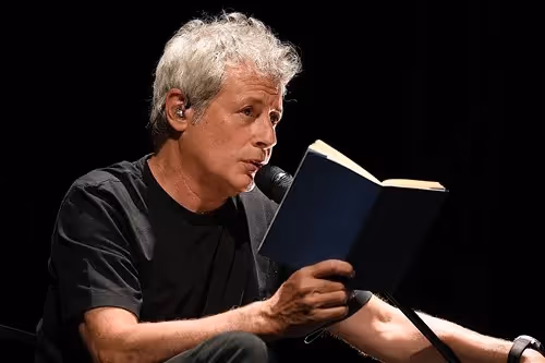 Reader performing at Festival di Spoleto, reading from an open blue book