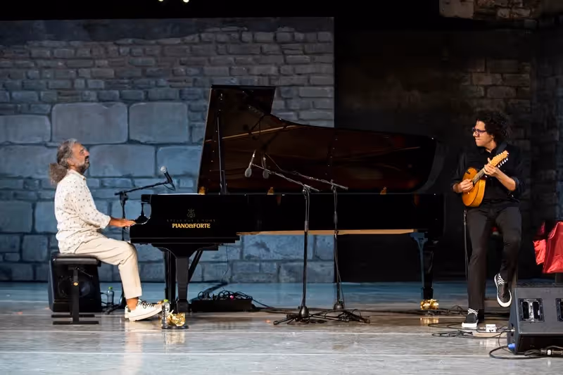 Pianists performing at Festival di Spoleto, sharing musical moment on stone stage