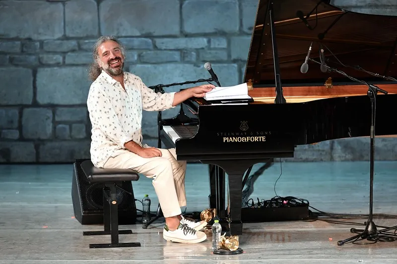 Pianist performing at Festival di Spoleto, smiling by grand piano on stone stage