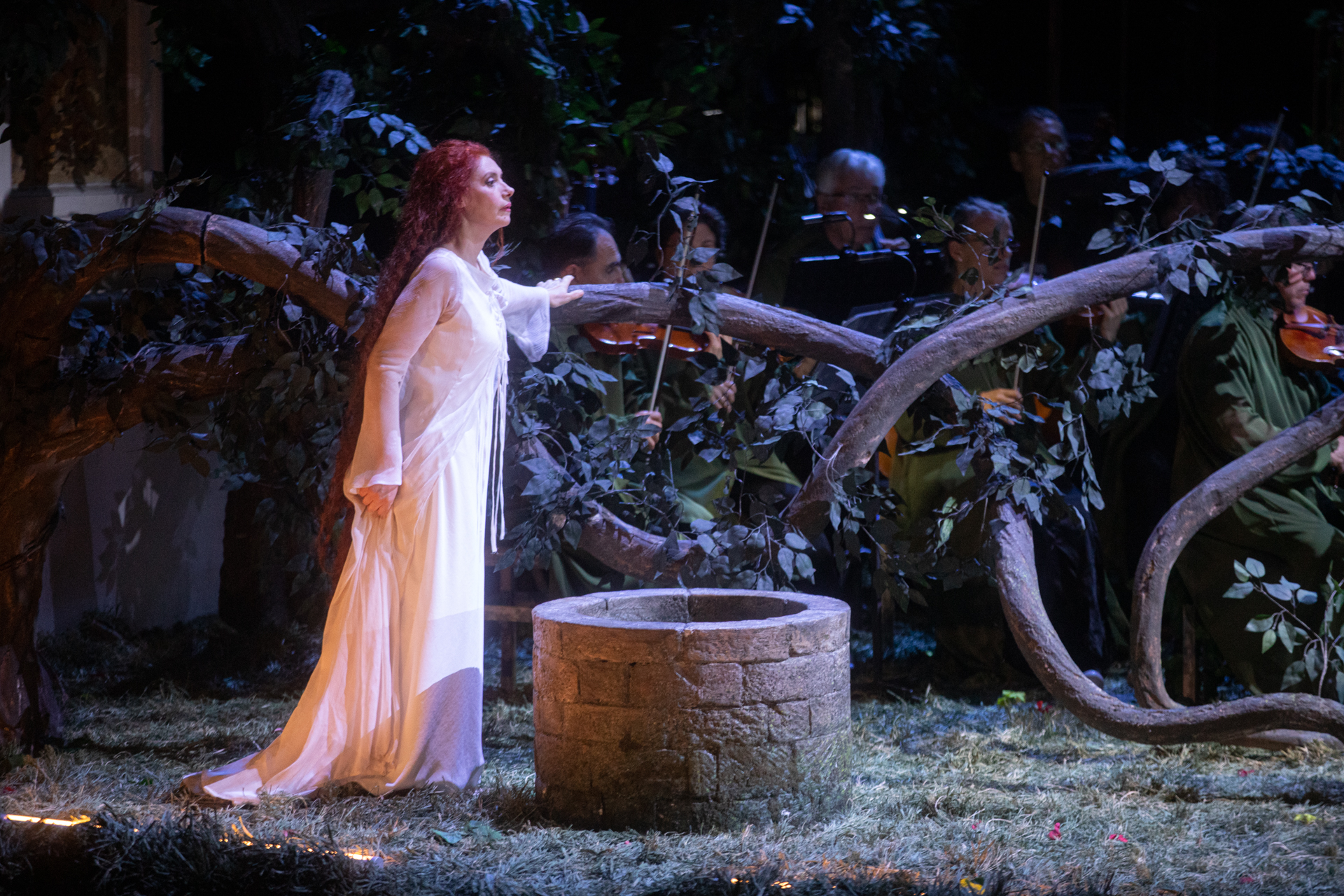 Performance teatrale al Festival di Spoleto con donna in bianco e pozzo antico