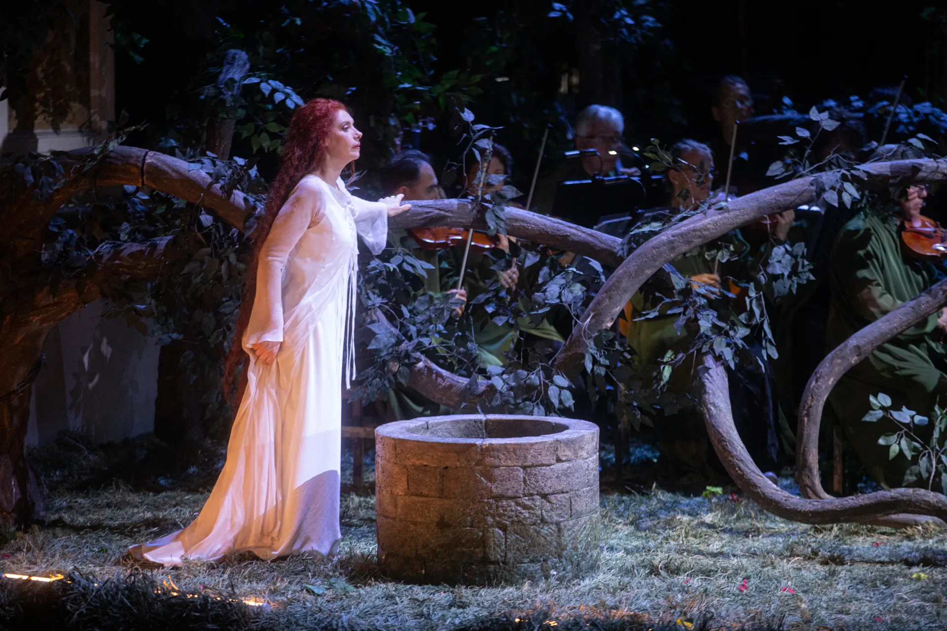 Festival di Spoleto performance with woman in white near stone well, orchestra