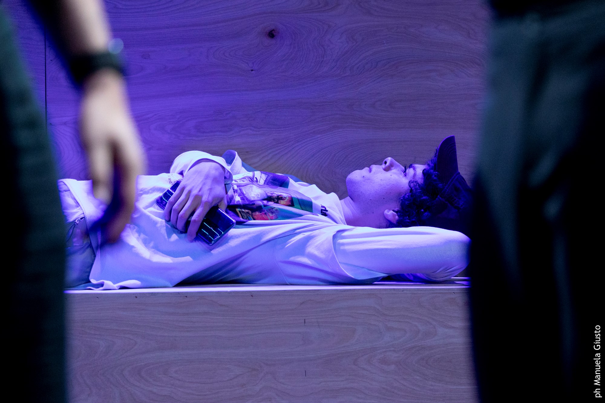 Performance artistica al Festival di Spoleto, performer sdraiato in luce viola