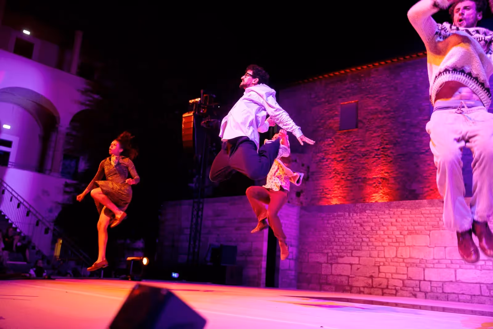 Energetic dancers performing at Festival di Spoleto under vibrant purple lighting