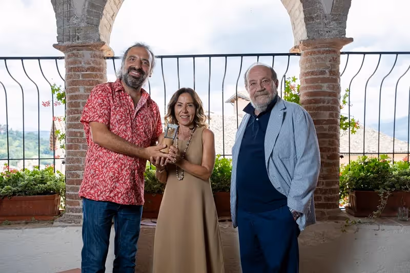 Festival di Spoleto artists pose together under stone archway with scenic view