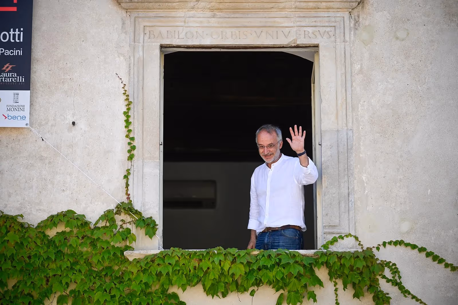 Ospite saluta dal balcone al Festival di Spoleto, circondato da edera verde