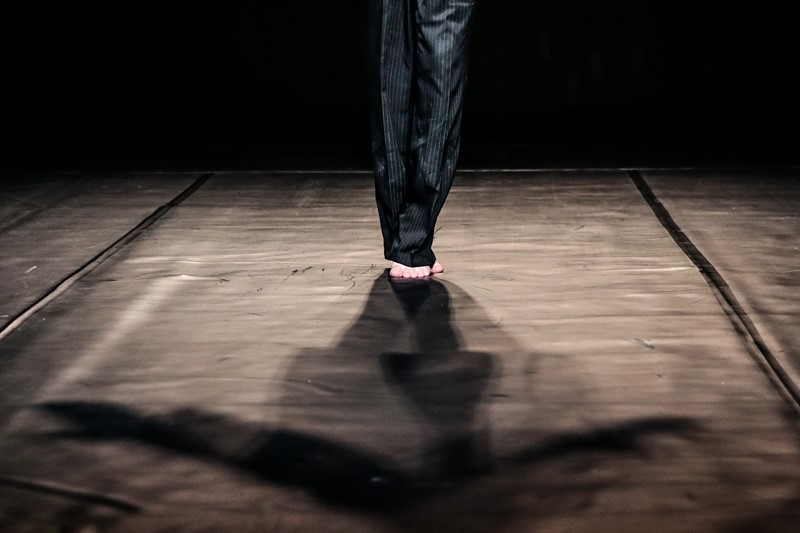 Festival di Spoleto performer's feet on wooden stage, dramatic shadow cast