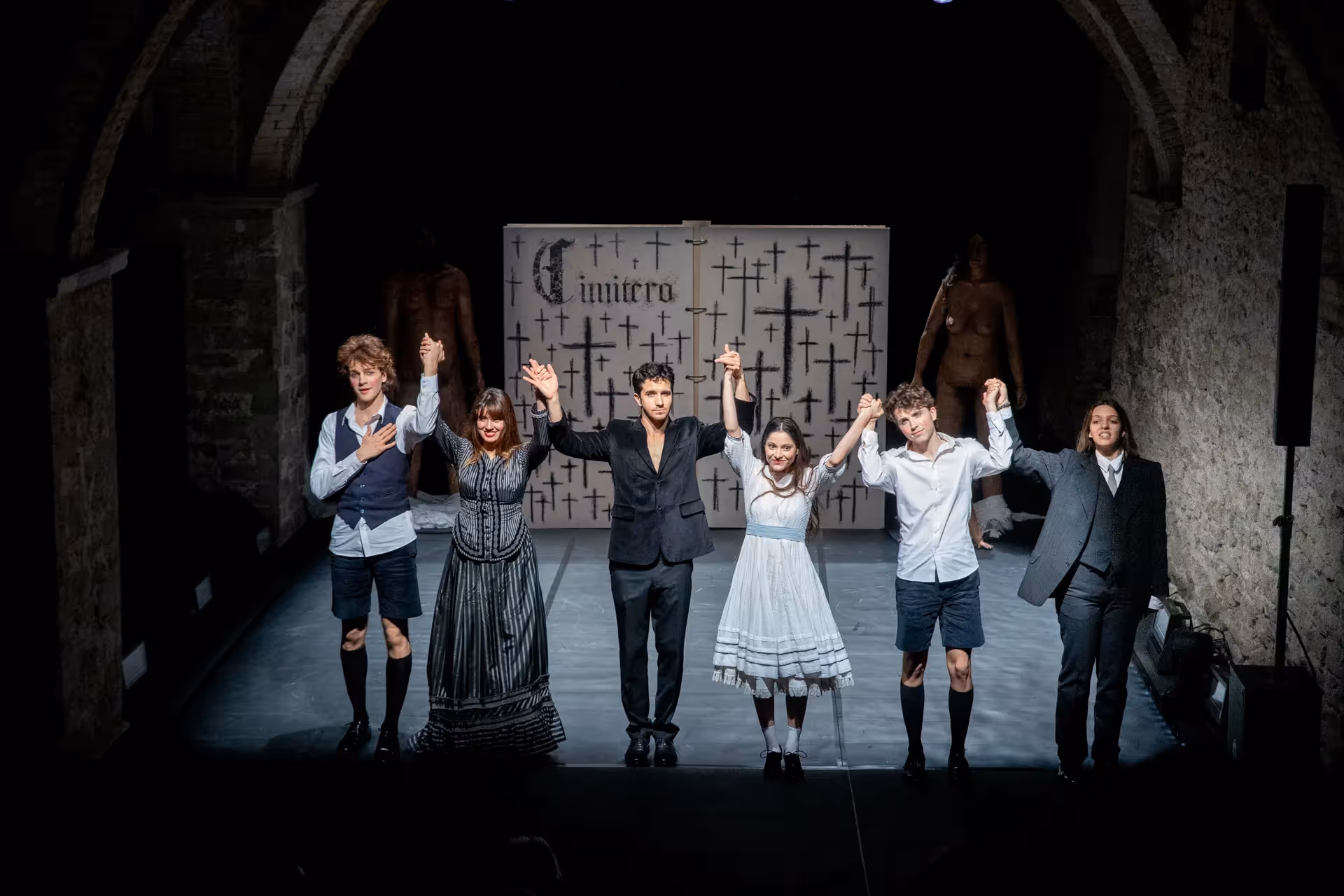 Attori sul palco al Festival di Spoleto, uniti davanti a sfondo di croci