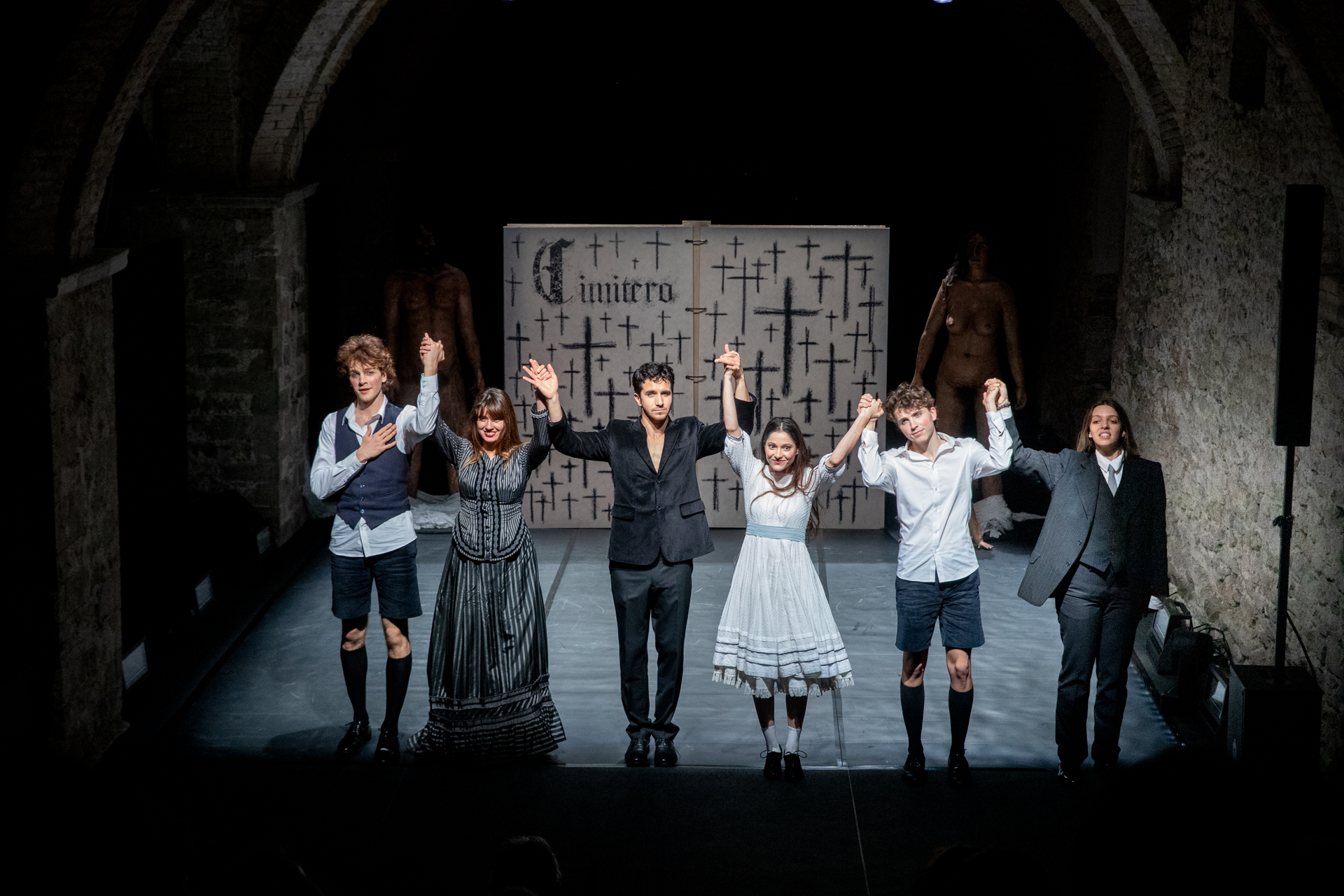 Attori sul palco al Festival di Spoleto, uniti davanti a sfondo di croci