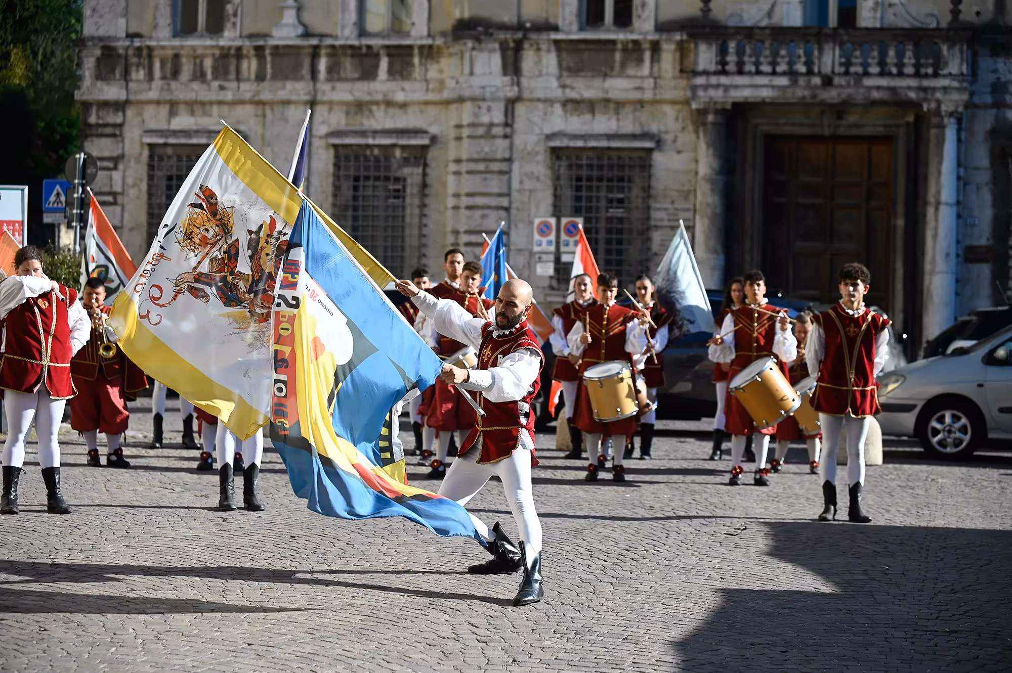 Colorful Festival di Spoleto performers waving flags in historic Italian square