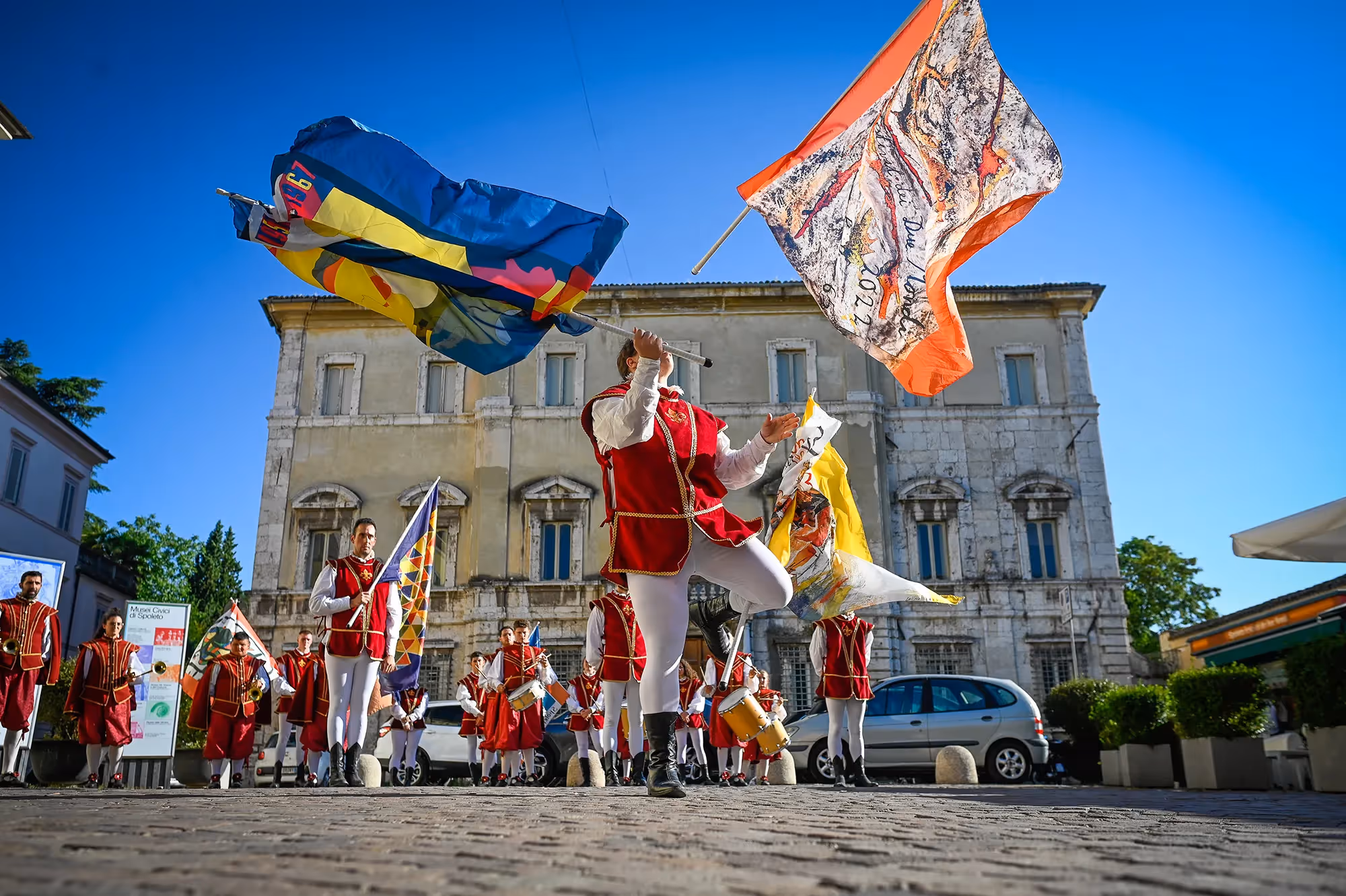 Colorful Festival di Spoleto performers waving flags in historic Italian square