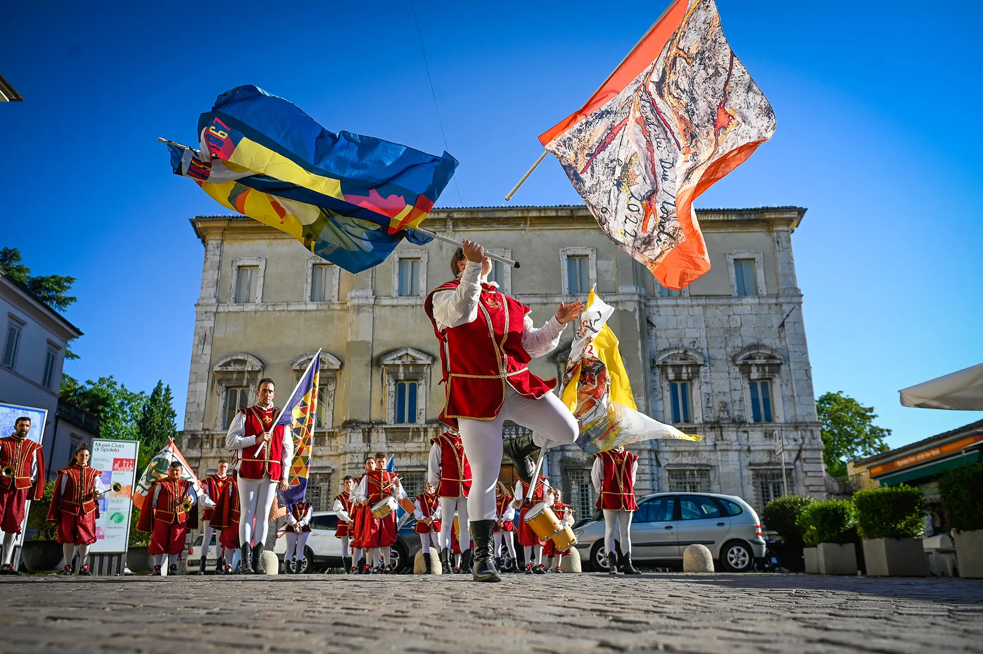 Colorful Festival di Spoleto performers waving flags in historic Italian square