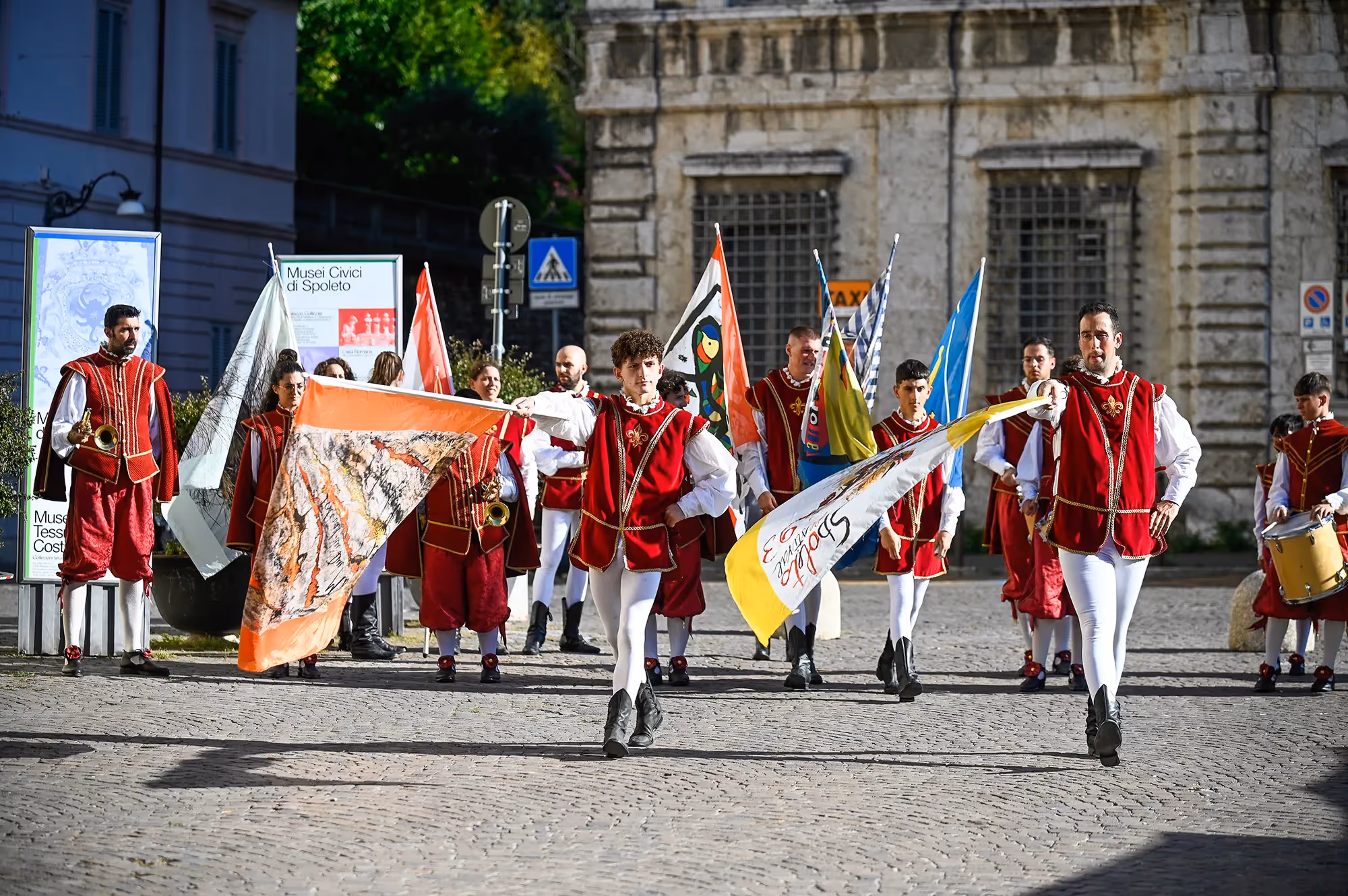 Festival di Spoleto performers in traditional red and white costumes parade with flags