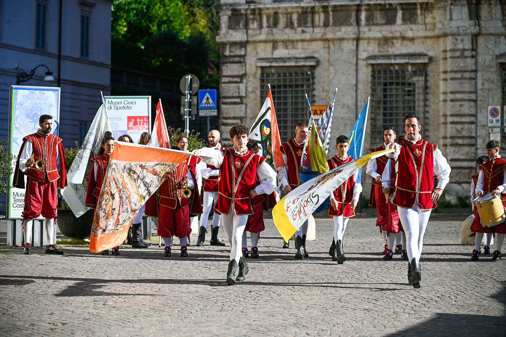 Festival di Spoleto performers in traditional red and white costumes parade with flags