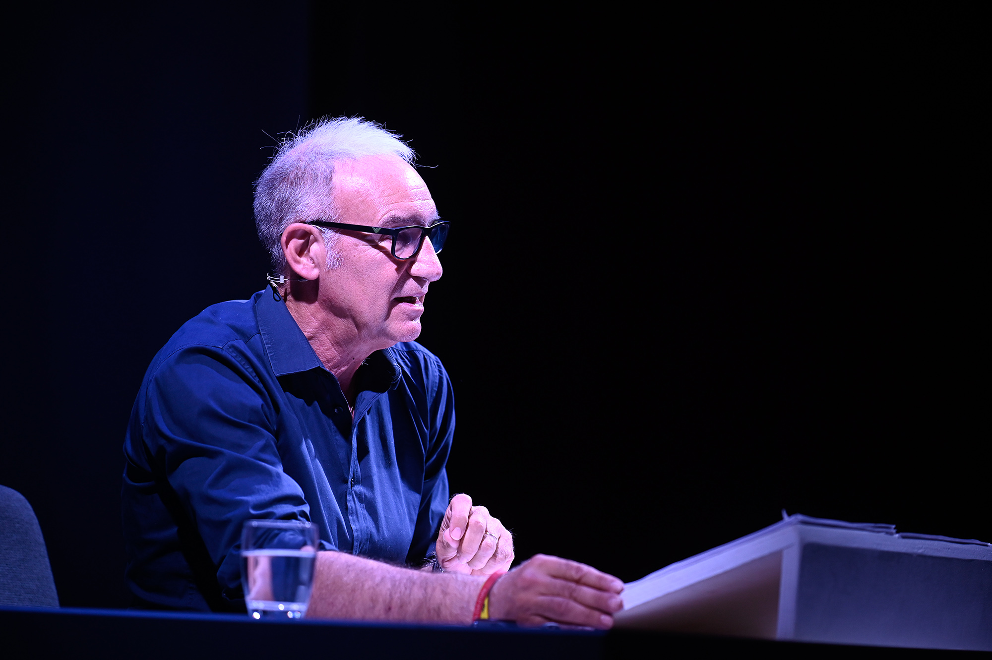 Speaker at Festival di Spoleto event discussing on stage with blue lighting