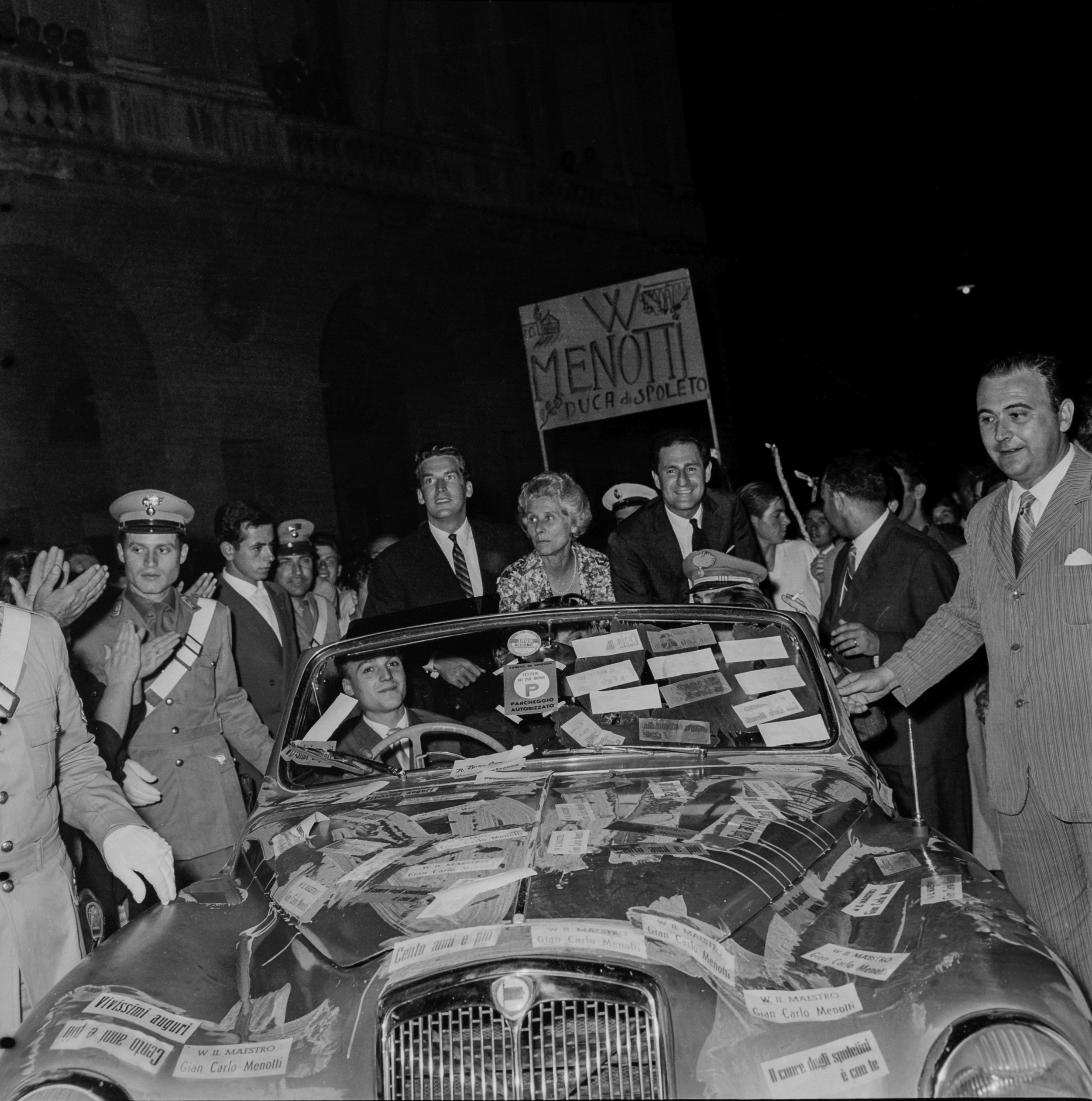 Macchina decorata al Festival di Spoleto con manifesti e persone intorno