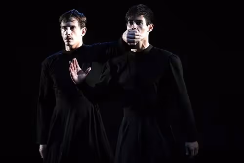 Two performers in black at Festival di Spoleto, dramatic stage lighting