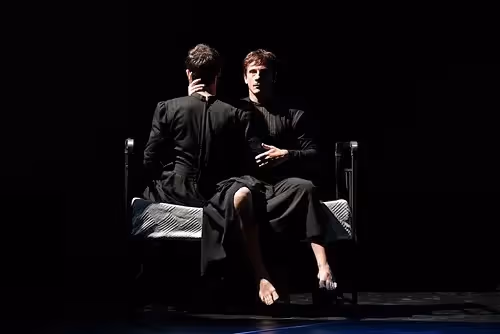 Two performers on stage at Festival di Spoleto, dramatic black minimalist scene