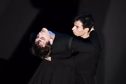 Festival di Spoleto performers in dramatic, intense theatrical pose against dark background