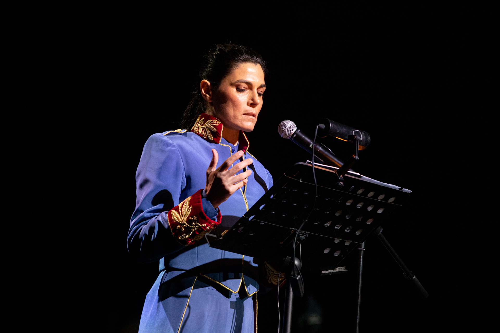 Performer in blue uniform speaking at Festival di Spoleto cultural event