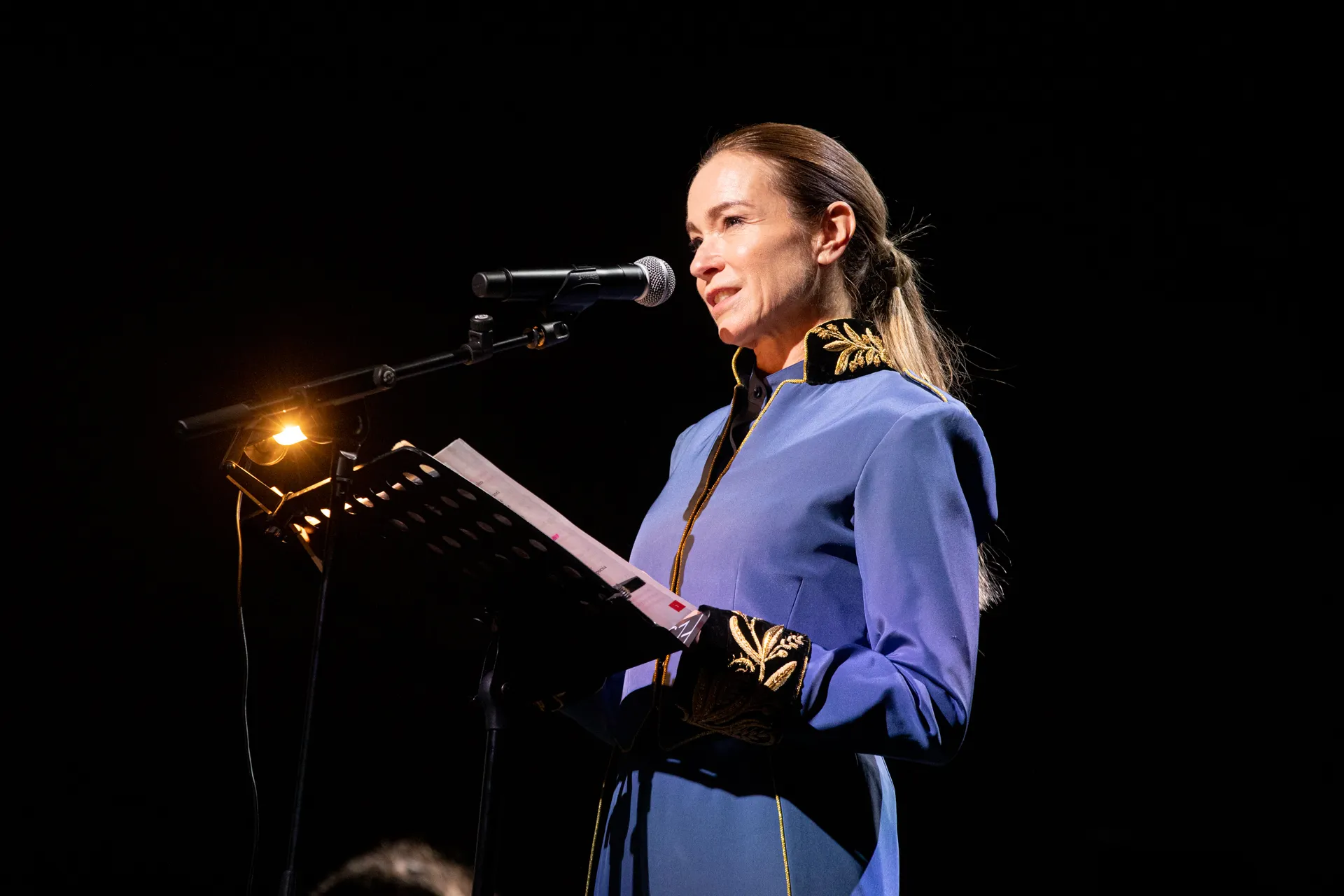 Performer in blu al Festival di Spoleto, legge dal palco illuminato