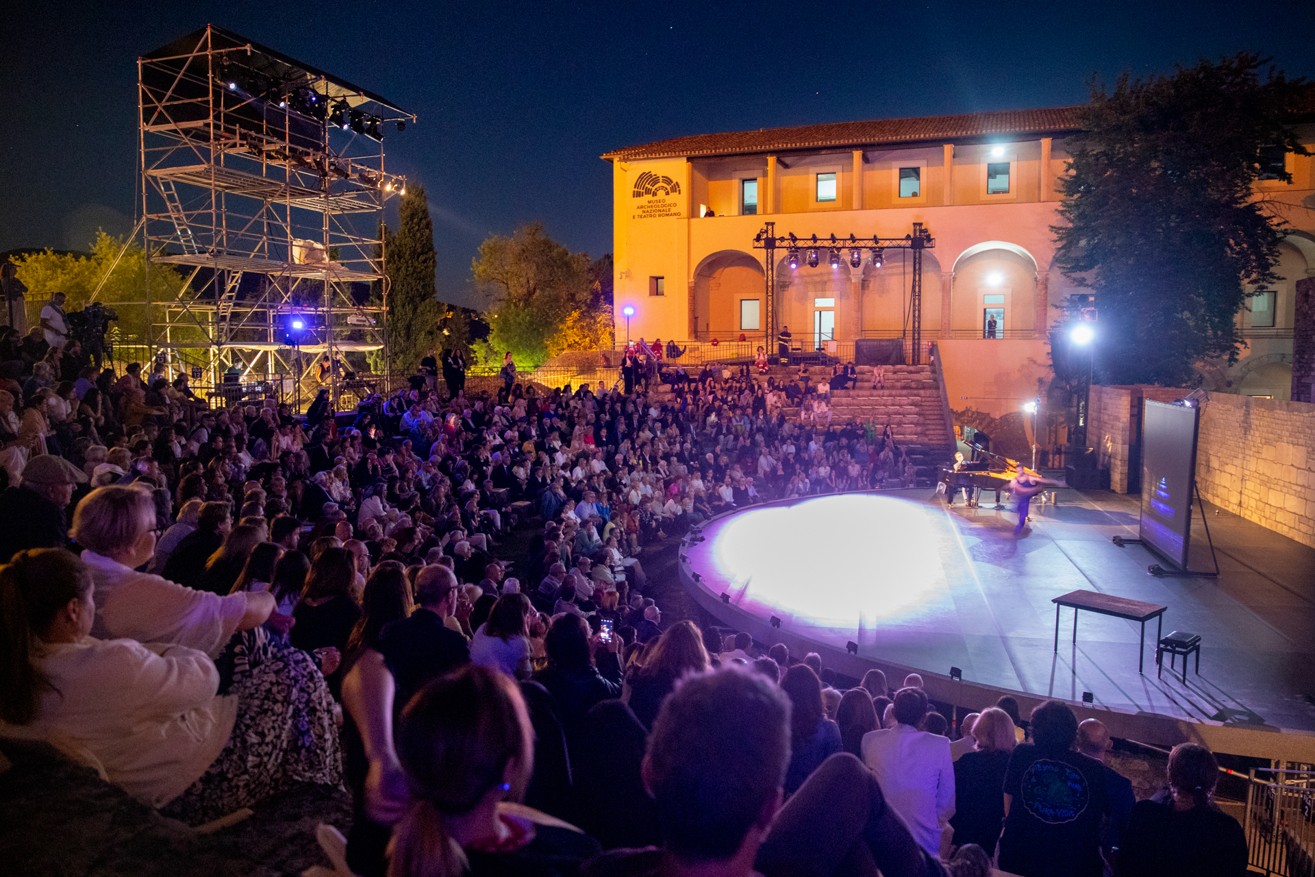 Spettacolo notturno affollato al Festival di Spoleto con palcoscenico illuminato