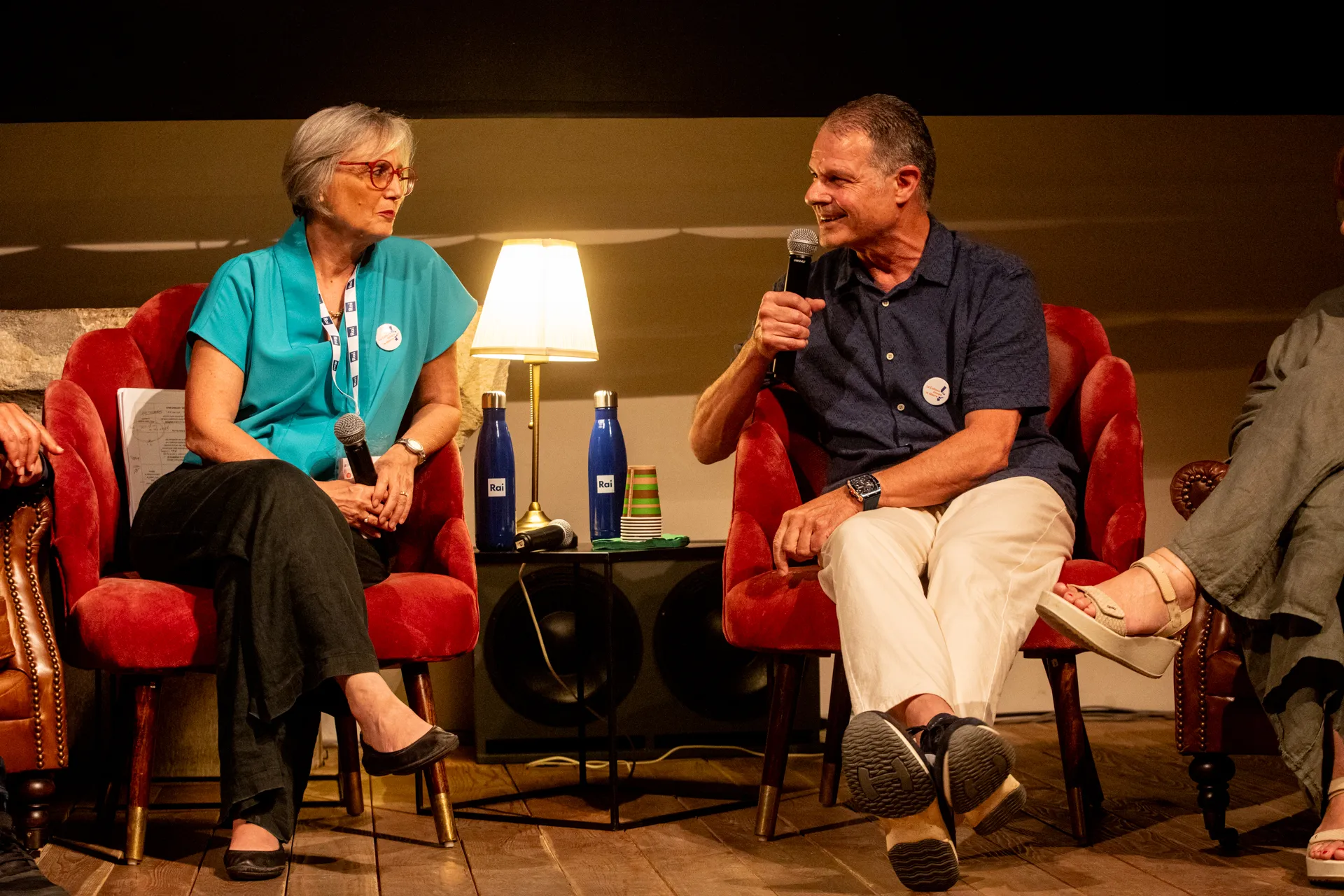 Two speakers at Festival di Spoleto discuss on stage with red chairs