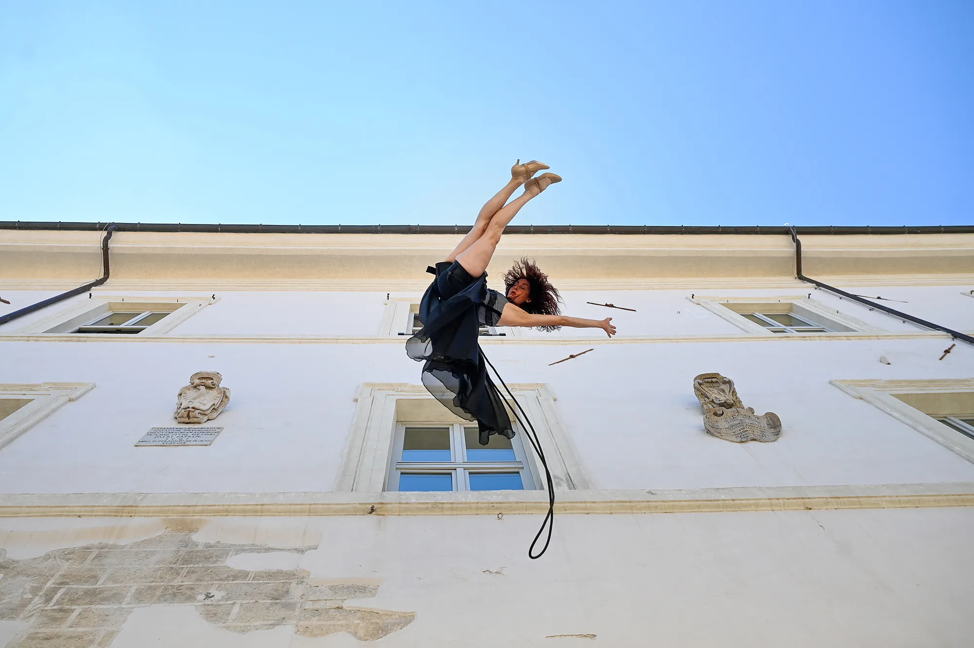 Dynamic performer leaps during Festival di Spoleto against historic white building