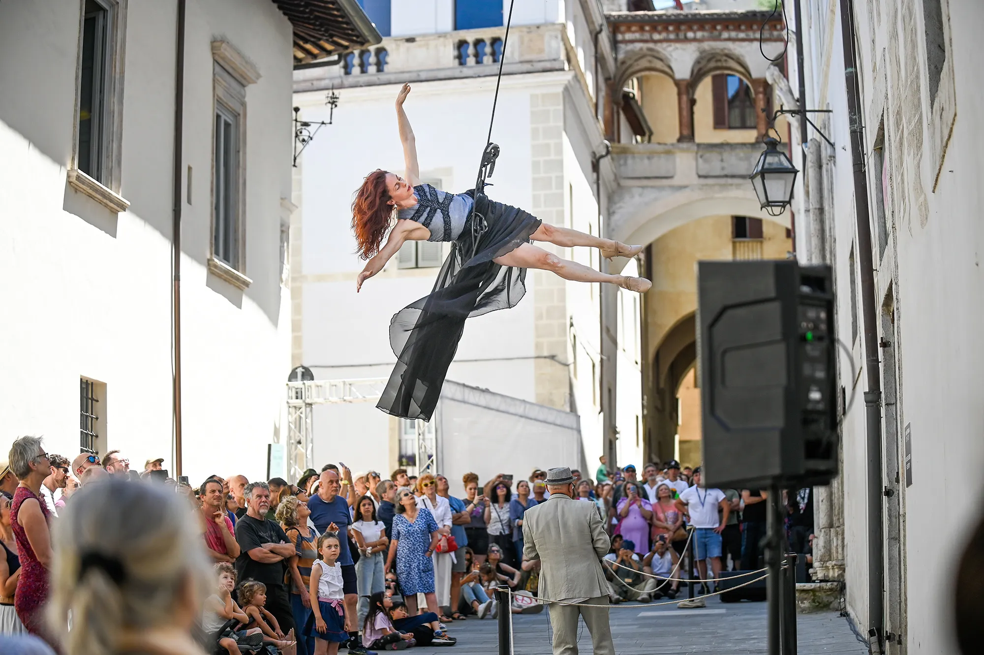 Aerial dancer performs at Festival di Spoleto, captivating crowd in historic Italian street
