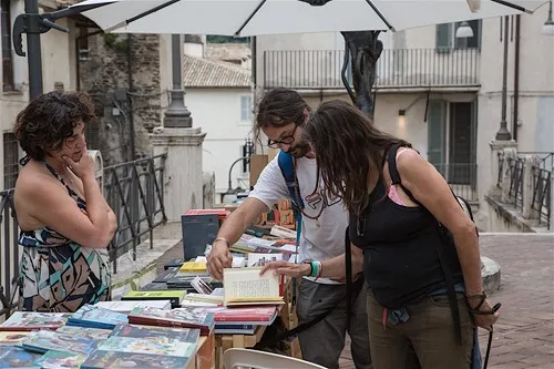 Persone al Festival di Spoleto sfogliano libri in una pittoresca piazza storica