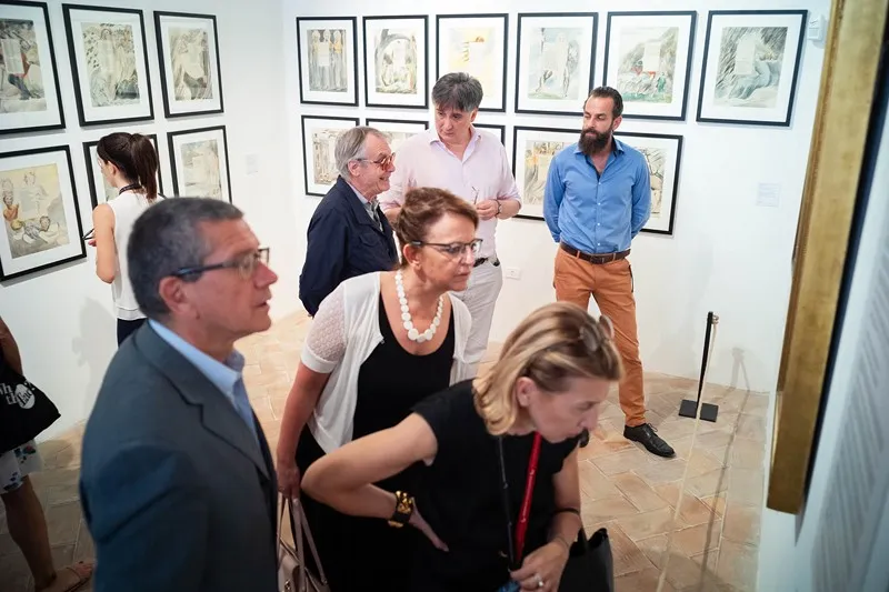 Visitatori alla mostra d'arte del Festival di Spoleto, galleria con opere incorniciate