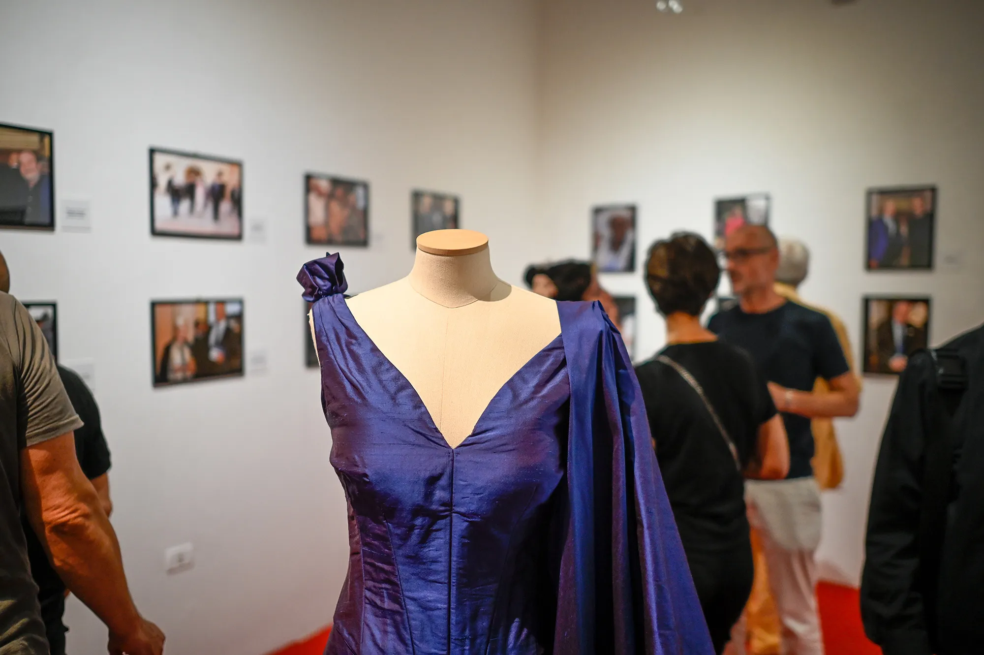 Blue gown displayed at Festival di Spoleto exhibition with portraits in background