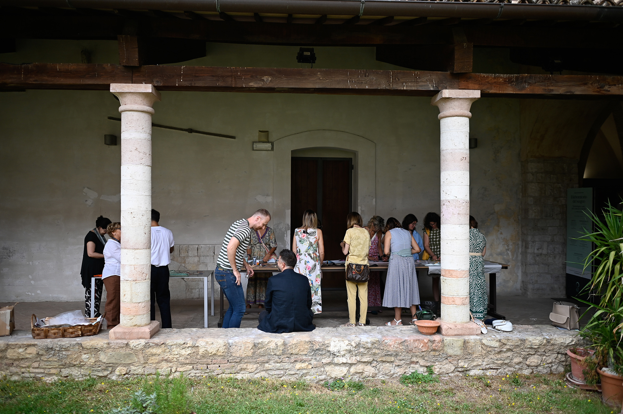 Visitors exploring exhibit at Festival di Spoleto in historic stone-columned venue
