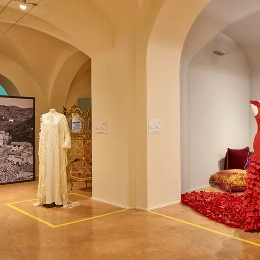 Festival di Spoleto exhibition showcasing vintage dresses in arched gallery space
