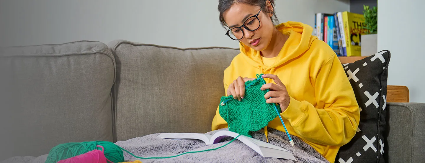 woman learning how to knit by reading for dummies book