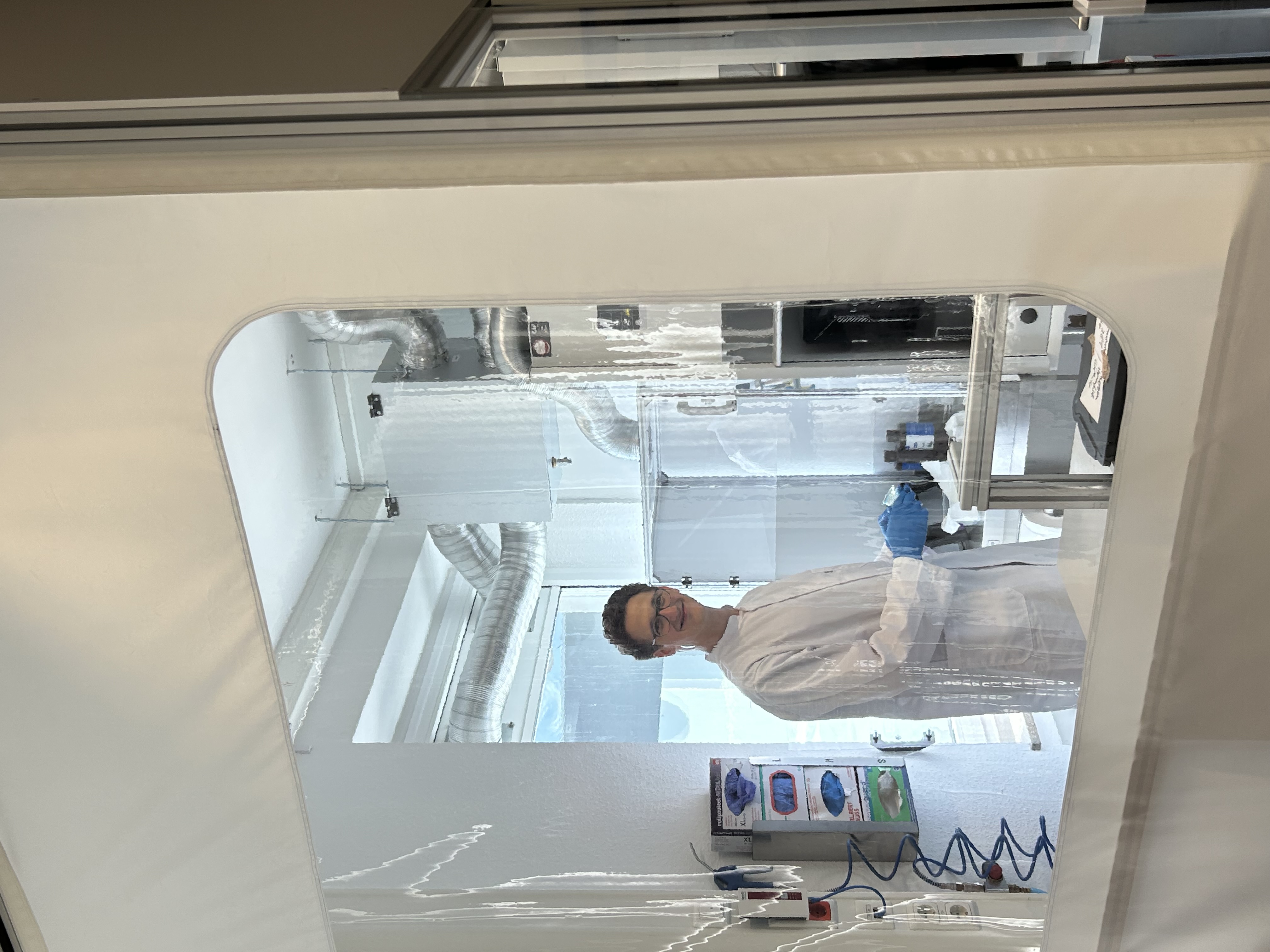 Mitarbeiter der evos schaut durch ein Fenster in der textilen Wand des 3D-Druck-Raumes