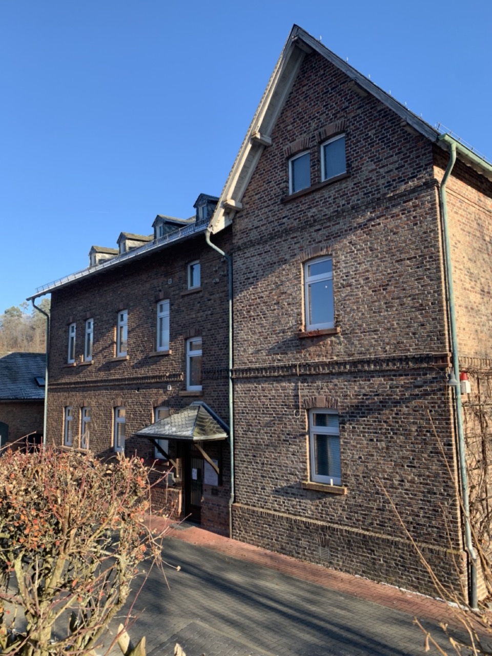 Außenansicht des Praxisgebäudes aus rotem Backstein mit Eingang zur Zahnarztpraxis.