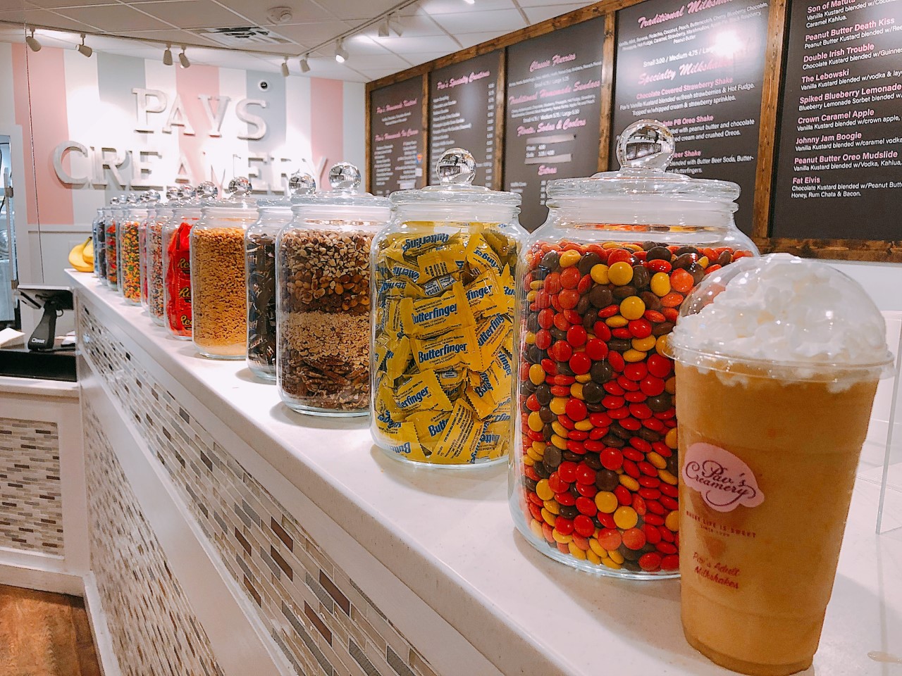 A picture of the inside of Pav's Creamery with sweet treats of several kind on the countertop and beautifully written menus on the walls.