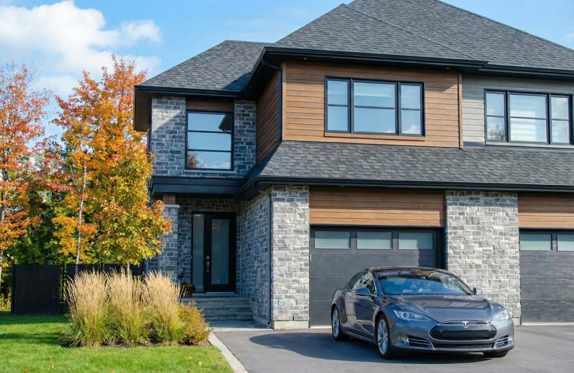Maison moderne en pierre et bois avec véhicule électrique Tesla stationné dans l'entrée