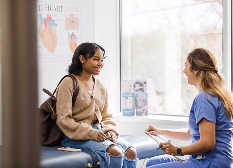 Patient smiling during medical consultation with heart anatomy poster background