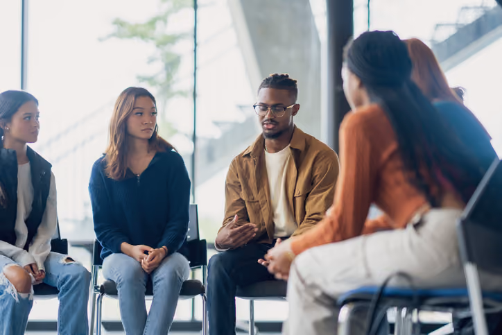 Diverse group of people sitting in chairs having a group discussion
