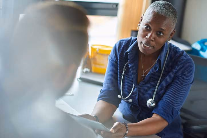 Healthcare professional in blue attire listens attentively during medical consultation